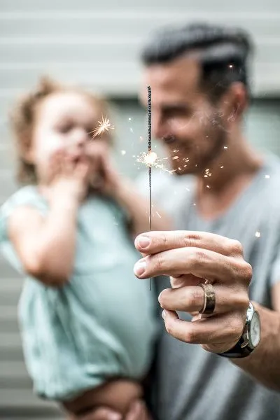 Image of a Man Holding a Child While Using Sparklers